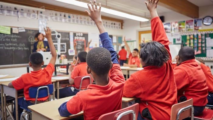 maestros en un salón de clases levantando la mano estudiantes